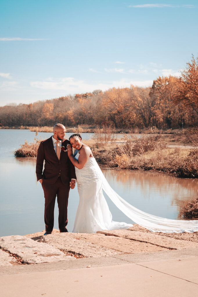 a newly wed couple standing nearby a lake with a beautiful background captured by san antonio event photographer