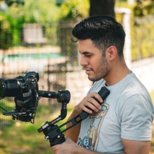 image showing a candid portrait of Xavier Chavez holding a nikon camera with a stabilizer capturing footage for a local murrieta roofing company