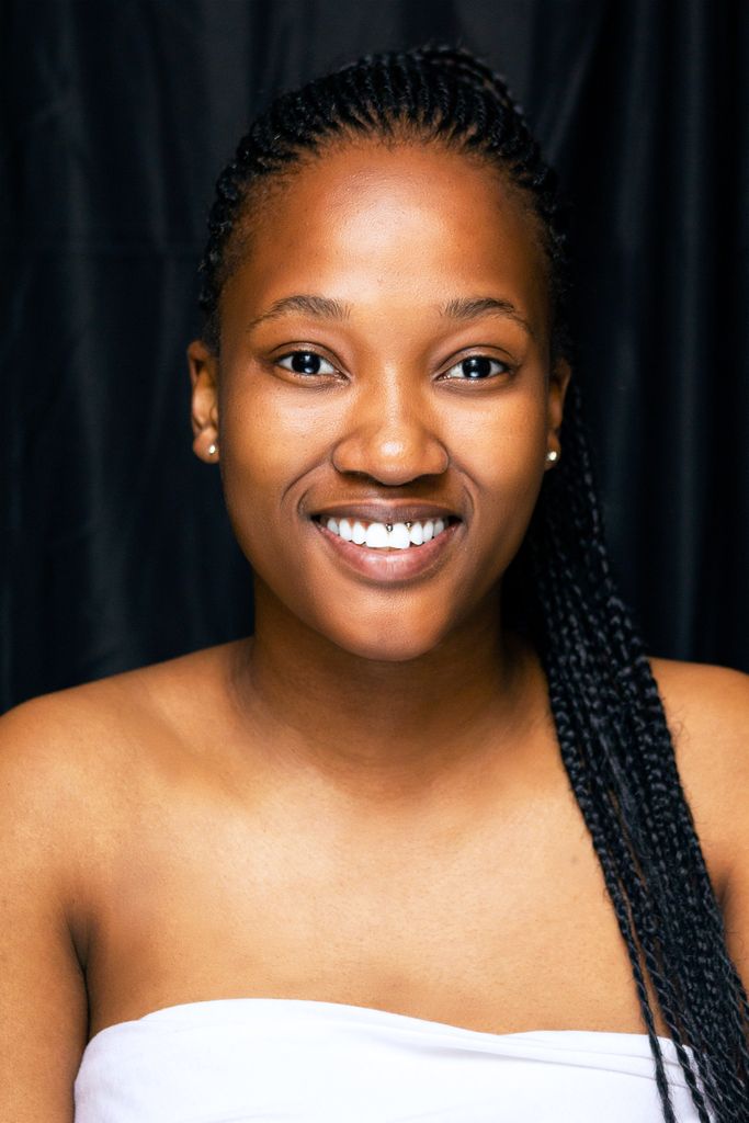 Close-up portrait of an adult woman with braided hair, smiling against a black background.